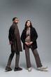 Leinwandbild Motiv full length of stylish interracial models in trendy autumnal outfits posing together on grey.
