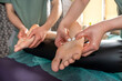 © RomanR - Two massage therapists woman and man give a double foot and leg massage to girl in spa salon.