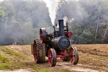 Wall Mural - Old steam engine moving through rural farm field.