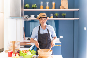 happy asian man cooking healthy food. handsome gentleman making salad for breakfast and dinner with fresh ingredients. fun cheerful male home cook preparing delightful vegetable for delicious salad