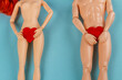 Naked male and female dolls holding red hearts covering thier groin. Love or valentines day concept. Blue background with copy space.