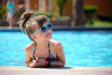 Happy Child Girl Relaxing On Swimming Pool Side On Sunny Summer Day