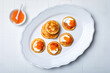 Festive appetizer. Mini Blini pancakes with sour cream and red caviar. Gourmet party food