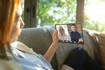 Wall Mural - Asian woman with blond hair video conferencing with coworkers over digital tablet in office