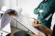 © Maya Photos - Inspector writting on a clipboard. Man in the background with arms crossed. Inspection by supervisors in a office