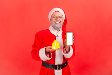 Wall Mural - portrait of smiling elderly man with gray beard wearing santa claus costume holding small paper hous