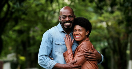 Wall Mural - African couple embracing together outside portraits looking at camera standing outside