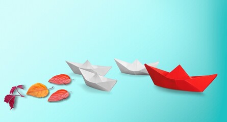 Wall Mural - Paper boat with fresh tree leaves on blue background.