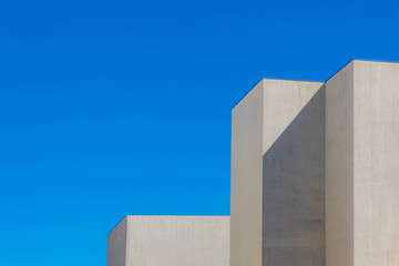 Minimalist photography with gromit building concrete building under blue clear sky, White grey geometric cement pole in minimalist, Modern architecture background.