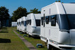 A row of white touring caravans on standing on a sunny day in summer.
