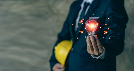 Close-up of a man holding a glowing light bulb with icons of ideas, innovation and business inspiration. Cyber ​​digital data saves energy