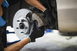 © Byrd Setta - Auto mechanic installing car front brake caliper and brake pads.