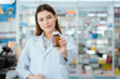© 2B - A young pharmacist handed a box of pills to the box with a smile in the pharmacy.
