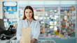 © 2B - A young pharmacist presents a paper bag containing medicines to sell in a general pharmacy.