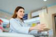 © 2B - A young pharmacist presents a paper bag containing medicines to sell in a general pharmacy.