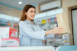 © 2B - A young pharmacist presents a paper bag containing medicines to sell in a general pharmacy.