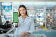 © 2B - Young pharmacist standing smiling looking at the camera holding a phone in front of a green screen