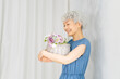 © metamorworks - 花籠を持って微笑むグレイヘアの女性
