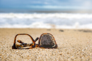 Sunglasses trash thrown in the sea on the sand