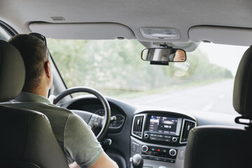 Wall Mural - Young man holding steering wheel while driving car. Road trip. Local travel concept. Thirst for adventure.