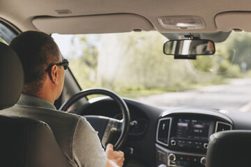 Wall Mural - Young man holding steering wheel while driving car. Road trip. Local travel concept. Thirst for adventure.