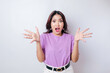 A portrait of a shocked Asian woman wearing a lilac purple t-shirt, isolated by a white background