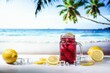 Closeup of a red summer drink in transparent glass and yellow lemons with a topical beach background