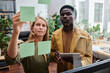 © pressmaster - Young confident businesswoman pointing at notepaper with working tasks while standing next to colleague in front of noticeboard