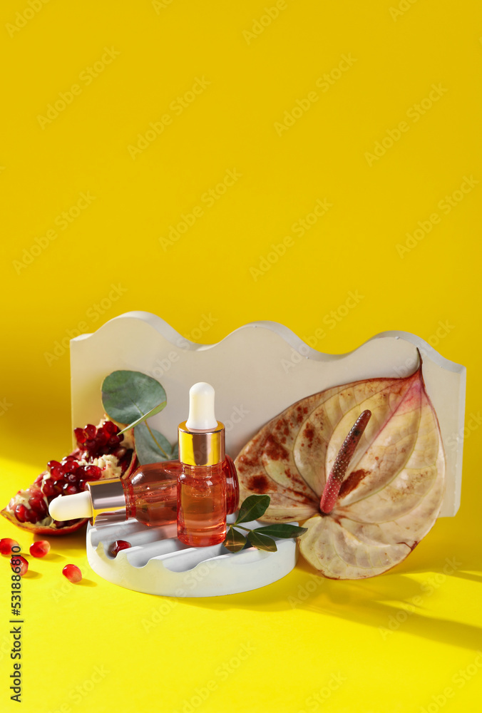Composition with bottles of essential oil and plaster decor on yellow background