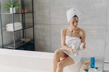 Wall Mural - Female applying moisturizing skincare cosmetics for body skin after taking a shower in bathroom