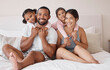 © Lumeez I/peopleimages.com - Young couple smile on bed, with children in their home or apartment. Happy multicultural family, in bedroom with toddler kids while on weekend vacation or holiday together for portrait