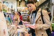 © PR Image Factory - asian Japanese girl traveler holding and comparing handmade handkerchiefs displayed in a shop while buying souvenir on teramachi street at nishiki market in Kyoto japan