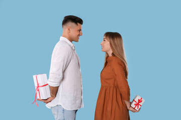 Wall Mural - Lovely couple exchanging gifts on light blue background. Valentine's day celebration