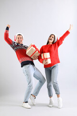 Poster - Beautiful happy couple in Santa hats with Christmas gifts having fun on light background