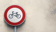 © Rioji - Round bicycle sign transit prohibited for bicycles on a building grey wall exterior background. Bicyle road sign, prohibition red sign, copy space.