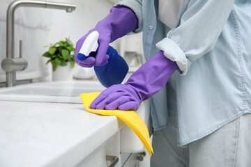 Poster - Woman cleaning white countertop with rag and detergent indoors, closeup