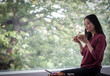 © Caia Image - Young woman eating with chopsticks at window