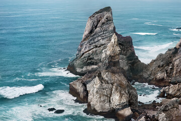 Background picturesque seascape with cliffs of Cape of Rock (Cabo da Roca) on the coast of Atlantic ocean in Portugal with wind, waves and splashes, the most western point of Europe, famous place