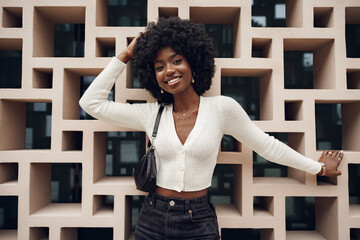 Stylish pretty african woman with hairstyle posing near geometric wall