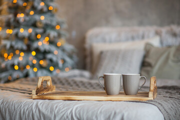 new year product mockup. cozy holiday decoration of house: Christmas tree, bed, garland with stars, tray with couple of cups and copy space. home decor