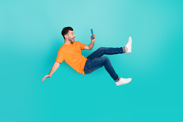 Full size photo of crazy blogger guy fall downward read network news isolated on cyan color background
