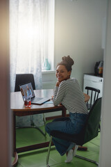 Wall Mural - through the door shot of young pretty woman smiling during online video call on laptop at home