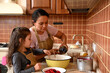 © Taras Grebinets - Mom and daughter cooking together, preparing dough for homemade festive cherry pie. Charming woman pouring some oil into a vintage enamel bowl, adding ingredients. Baking concept. Family relationships