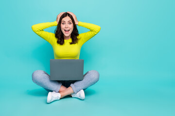 Canvas Print - Full body portrait of astonished pretty lady sit floor use netbook hands touch head isolated on teal color background