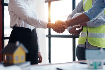 Architect and engineer work together and shaking hands to welcome home design projects to work in the same way and work together as a team.