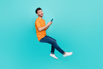 Wall Mural - Profile side full body photo of positive guy sit invisible chair blogging device isolated on cyan color background