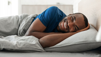 Wall Mural - Black Guy Posing Lying In Bed Smiling Resting At Home