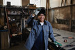 © Seventyfour - Waist up portrait of multiethnic female welder smiling at camera in industrial factory workshop, copy space