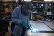 © Seventyfour - Side view portrait of female welder working with metal in industrial workshop, copy space