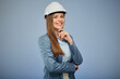 Smiling woman in white safety industrial helmet. Isolated female portrait. Business person in gray suit.